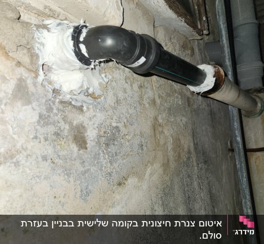 צינור פלסטיק שחור עם חיבור לקיר בטיח לבן